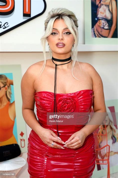 A Woman Wearing A Red Dress And Choker Posing In Front Of Pictures On