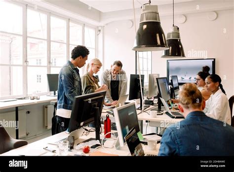 Creative business people working on computers in open plan office Stock ...