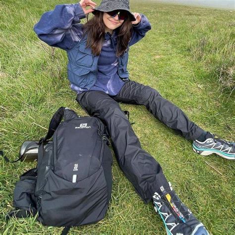 A Woman Sitting On The Ground With Her Skis And Backpack In Front Of Her