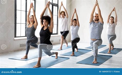 Diverse People Doing Warrior One Exercise At Group Yoga Lesson Stock