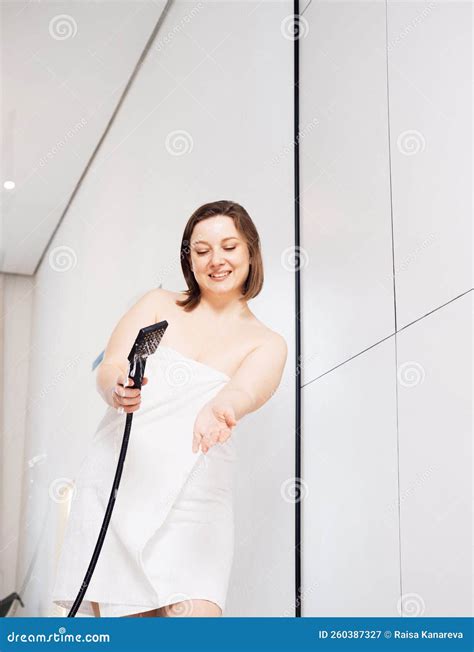 Smiling Woman Check Water Temperature in the Shower with Hand Shower