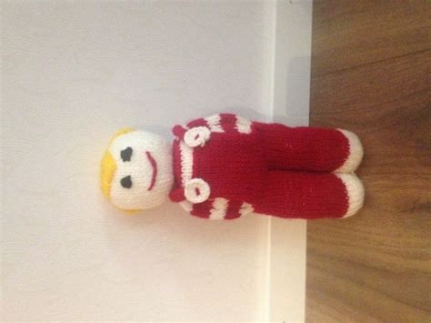 A Pair Of Red And White Knitted Gloves Hanging On The Wall