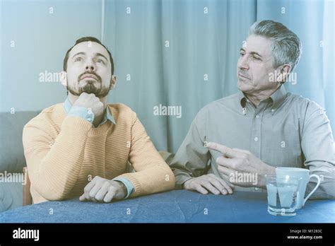 Mature Father And Son Is Serious Conversation At Table At Home Stock