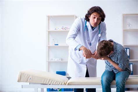 El Niño Herido En La Mano Visitando A Un Joven Médico Varón Niño Herido