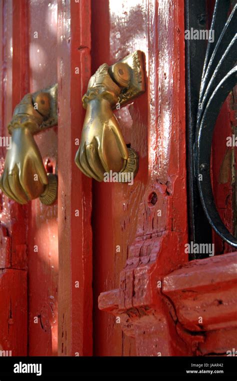 An Old Red Door With Two Golden Hand Like Knockers On It Stock Photo