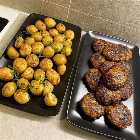 Two Black Trays Filled With Food On Top Of A Counter Next To A Stove