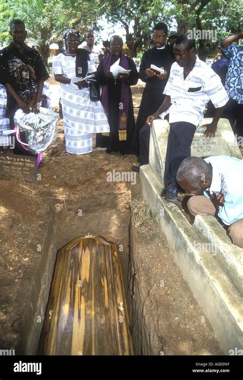 Mourners at a graveside with priest, Christian funeral service in Accra ...