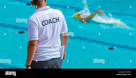 Back View Of Swimming Coaches Wearing Coach Shirt Watiching His Female