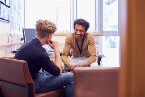 Male College Student Meeting With Campus Counselor Discussing Mental