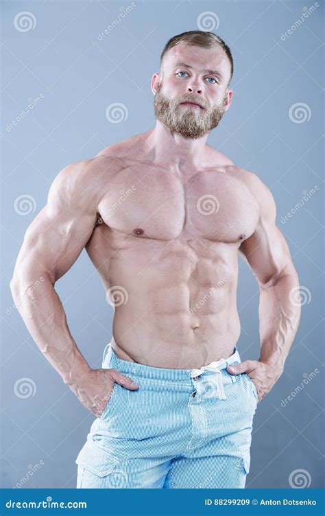 Brutal Strong Bodybuilder Man Posing In Studio On Grey Background