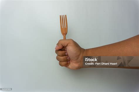 Hand Holding Wooden Spoon And Fork Isolated On White Background Stock