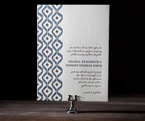 A White And Blue Wedding Card Sitting On Top Of A Wooden Table Next To