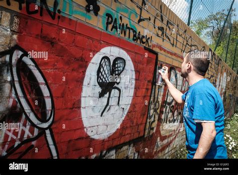 Graffiti artist Ibo Omari paints over swastika graffiti on a wall in ...