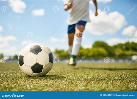 Menino Que Retrocede A Bola No Campo De Futebol Foto De Stock Imagem