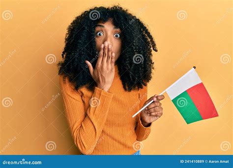 African American Woman With Afro Hair Holding Madagascar Flag Covering Mouth With Hand Shocked