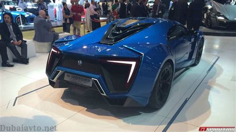 A Blue Sports Car Is On Display At An Auto Show With People Standing