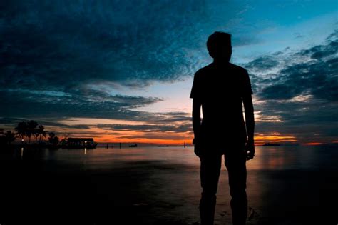 Premium Photo Silhouette Man Standing On Sea Shore Against Dramatic Sky