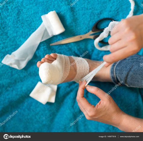 Woman Bandaging Her Injured Leg On Sofa At Home Stock Photo By