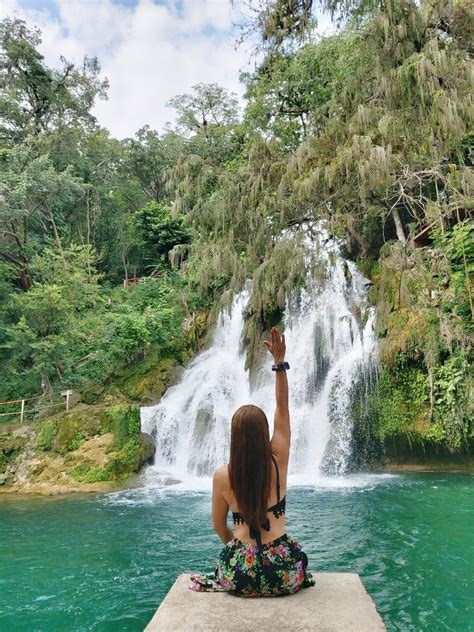 A Woman Sitting In Front Of A Waterfall