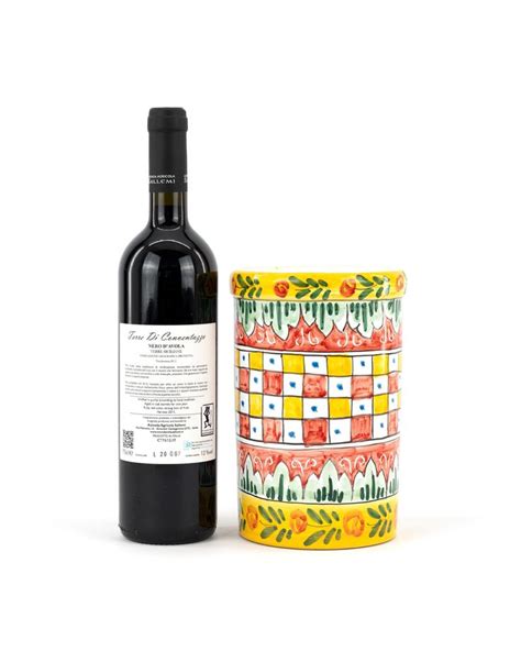 A Bottle Of Wine Next To A Ceramic Container With Flowers On It And A