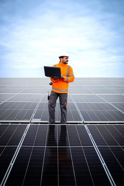 Engenheiro de usina de energia solar em pé no telhado laptop e