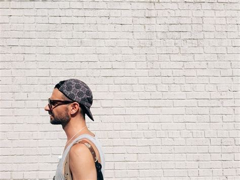 Premium Photo Side View Of Man Wearing Cap Standing Against Brick Wall