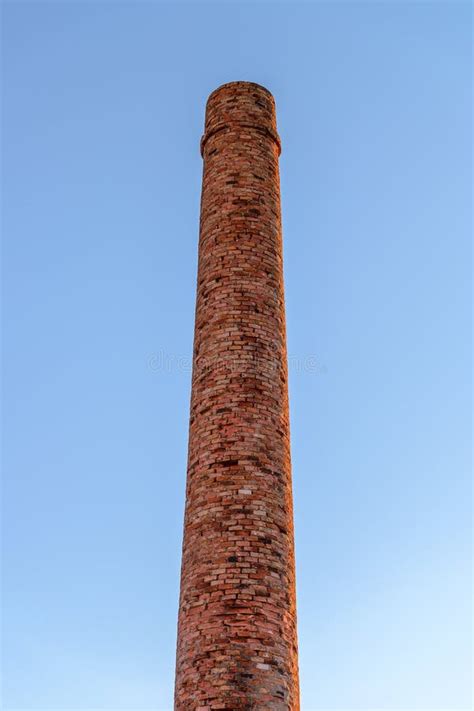 De Schoorsteen Van De Baksteenfabriek Tegen De Blauwe Hemel Stock Foto