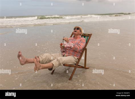 Senior Man Having Cocktail Drink While Relaxing In A Sun Lounger Stock