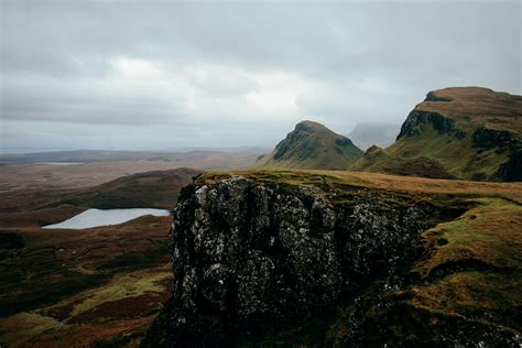 View Of A Cliff Overlooking Mountains A Lake Overcast Skies And Brown