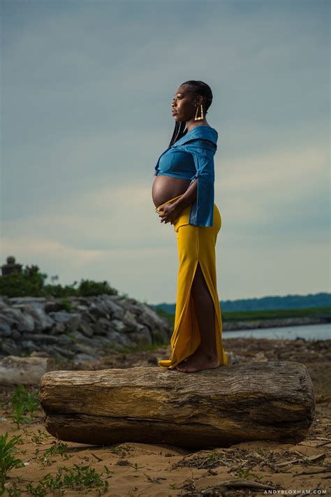 Itap Of A Pregnant Woman Standing On Top Of A Log By The Water