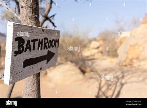 A Hand Painted Sign With An Arrow Shows The Way To An Open Air Bathroom