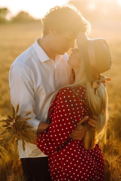 Retrato de una joven pareja feliz abrazándose en el campo al atardecer