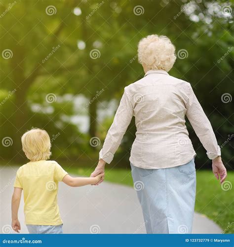Beautiful Granny and Her Little Grandson Walking Together in Park Stock