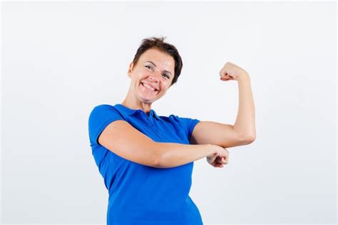 Femme Mature Montrant Les Muscles Du Bras En T shirt Bleu Et à La Joie