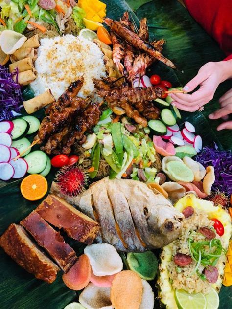 A Table Topped With Lots Of Different Types Of Food And People Reaching