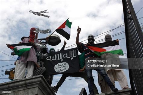 Kashmiri protesters hold up a flag of the Islamic State of Iraq and ...