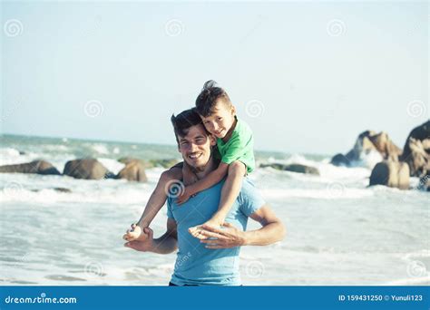 Familia Feliz En La Playa Que Juega Padre Con La Costa De Mar Del Hijo