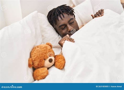 African American Man Lying On Bed Sleeping With Teddy Bear At Bedroom