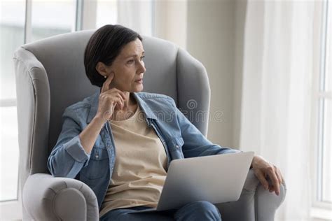 Thoughtful Mature Woman Sitting In Armchair At Home Stock Photo Image Of Internet Depress