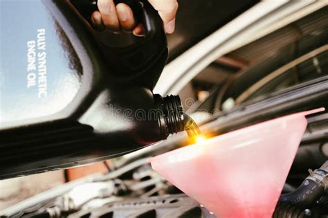 A Car Mechanic Is Pouring New Engine Oil Into A Funnel Into The Car