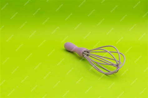 Premium Photo Purple Whisk For The Kitchen On A Green Background