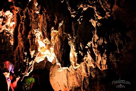 Two People Standing In Front Of A Cave With Light Coming From It S Ceiling