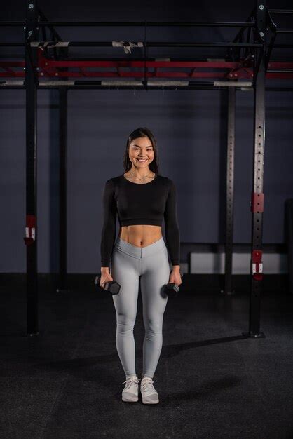 Mujer asiática haciendo ejercicios con pesas en el gimnasio Foto Premium