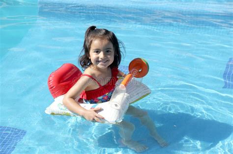 4 Year Old Latina Girl Swims In The Pool With An Inflatable Float Toy