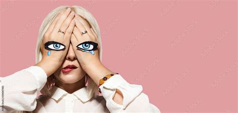 Sad woman crying. Girl closed eyes, eyes and tears painted on her hands. Portrait of fashionable ...