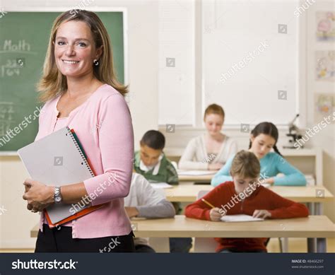 Teacher Standing With Notebook In Classroom Stock Photo 48466297