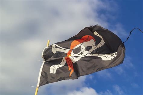 Pirate Flag `Jolly Roger` on a Background of Blue Sky with Clouds on a ...