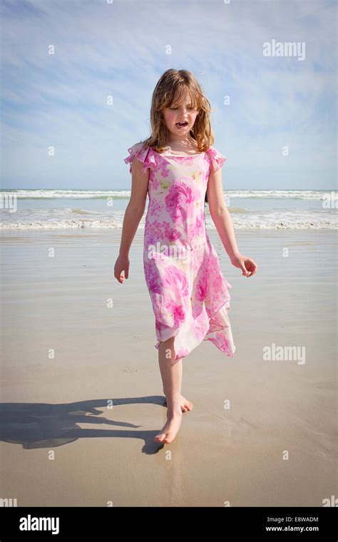 Pretty nine year old girl in a floral pink dress walking along the ...