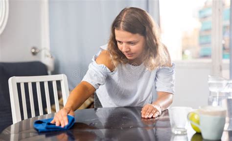 Mujer Joven Limpiando Mesa De Comedor En Casa Imagen De Archivo