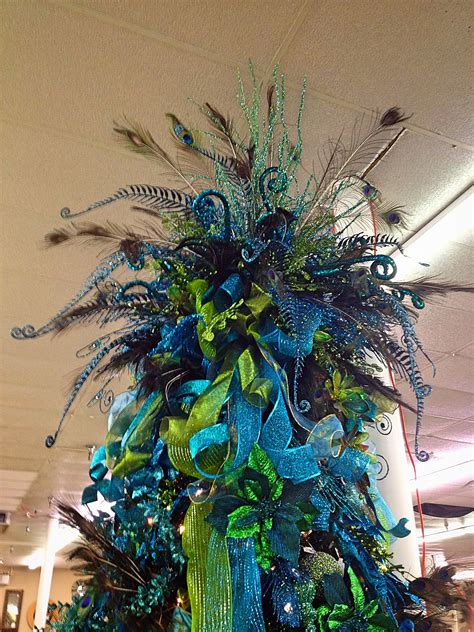 a blue and green christmas tree with feathers on it in an office building ornament